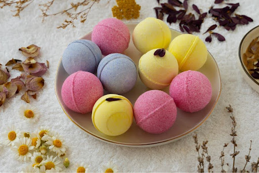 A colorful collection of aromatic bath bombs resting on a wooden tray next to a modern bathtub.
